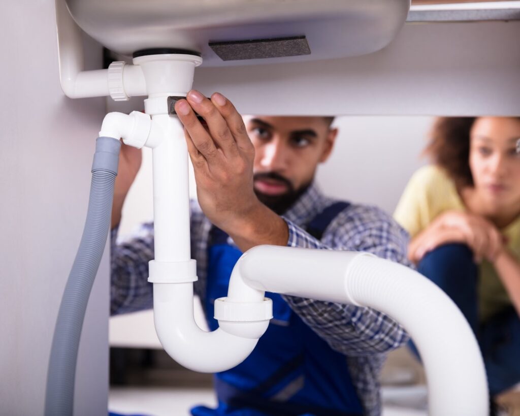 Plumber checking pipes under the kitchen sink.